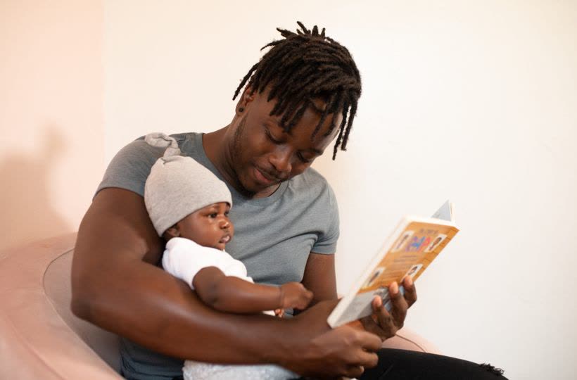A parent reading a printed activity book with their young child